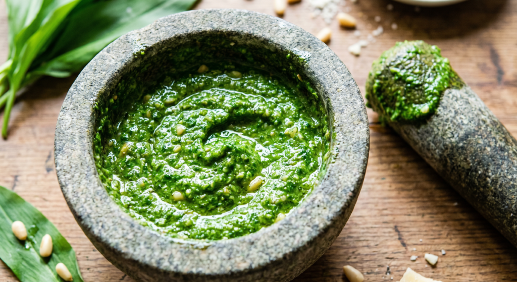 Cremiges, frisch zubereitetes Bärlauch Pesto im Steinmörser mit intensiver grüner Textur und glänzendem Olivenöl.