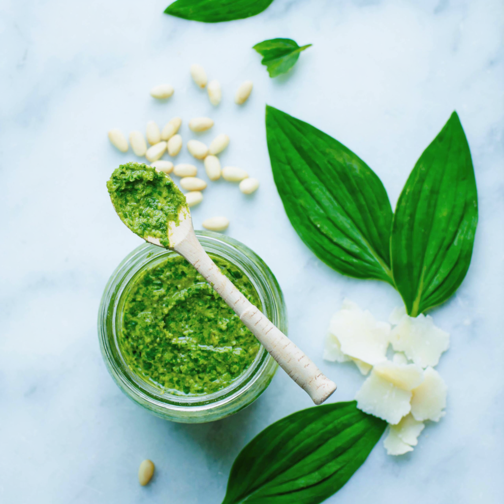 Selbstgemachtes Bärlauch Pesto im Glas mit frischen Bärlauchblättern und Pinienkernen